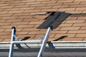 Fixing damaged roof shingles. A section was blown off after a storm with high winds causing a potential leak.