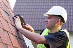 Roofing work, the worker with an instrument in the background a country house