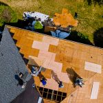 Aerial view of roof construction repairman on a residential apartment with new roof shingle being applied