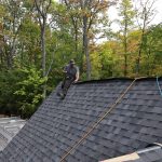 A man sitting on top of a shingle residential roofing