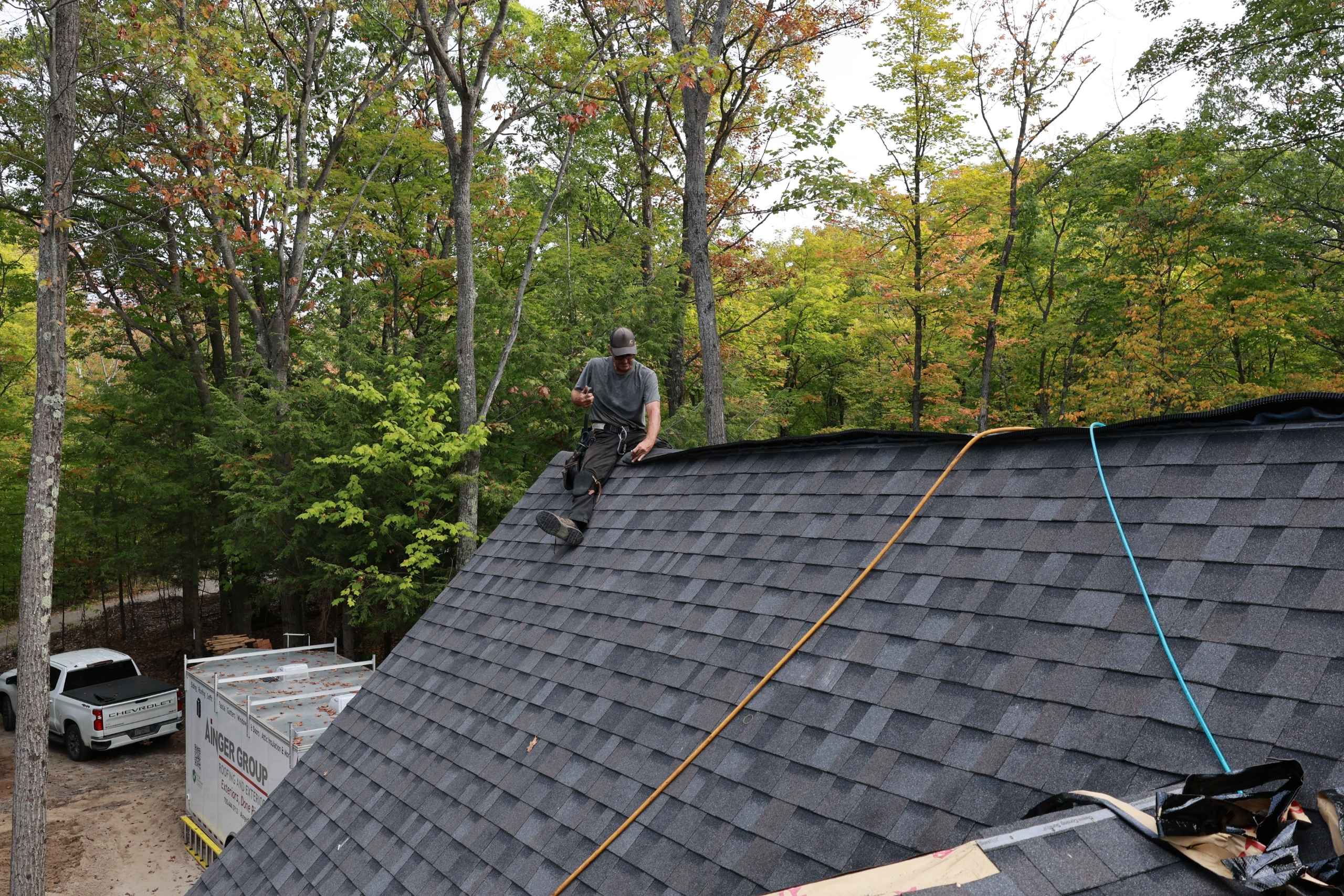Professional roofer installing a shingle roof in tiny