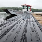 Ainger Group Flat Bottomed Boat travelling to Cottage roofing jobs, with metal roofing in front of it