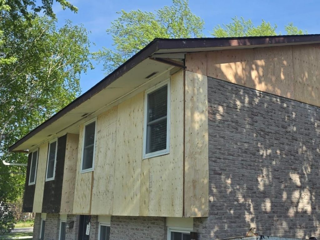 Inspecting the boards behind siding on a house