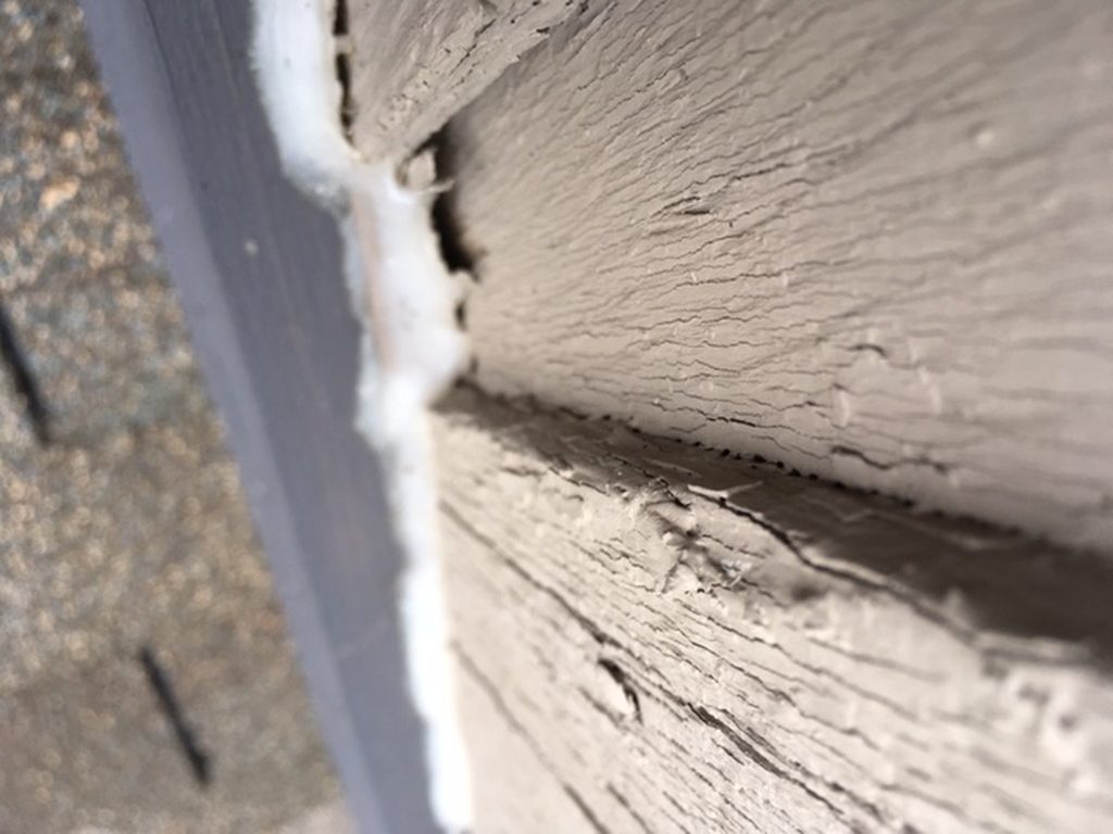 Close view of a failed seal beside chimney flashing on an Ainger roofing project.