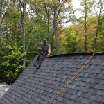 Ainger Group roofer working on a shingle roof surrounded by fall trees in Orillia.