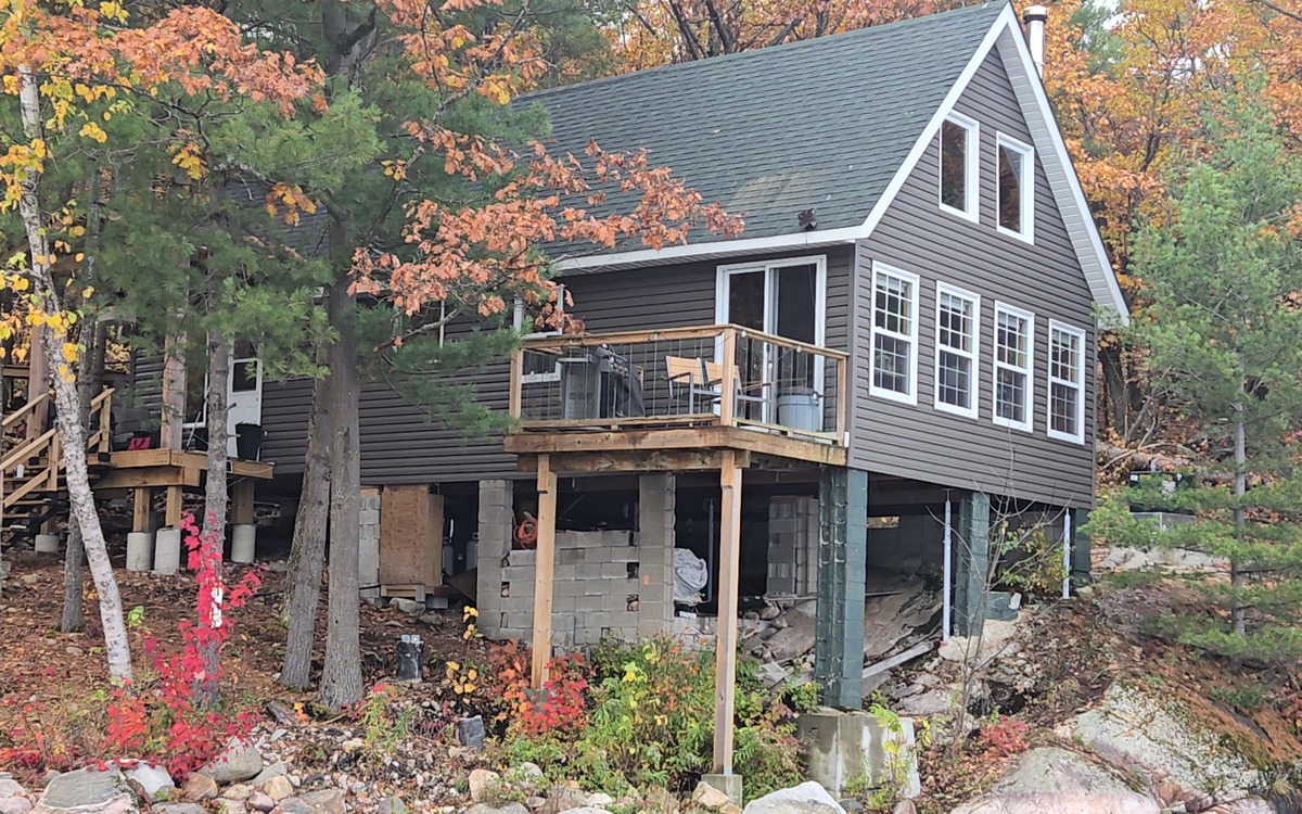 Finished Ainger siding project on a wooded lakeside cottage in Muskoka.